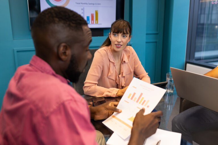 Discussing financial charts, colleagues collaborating in modern office meeting room. Business, finance, teamwork, collaboration, analytics, corporate