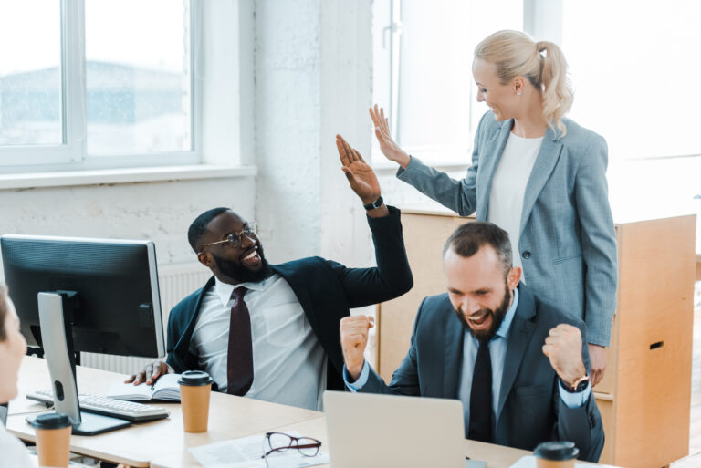 cheerful businesswoman giving high five to african american businessman near coworkers
