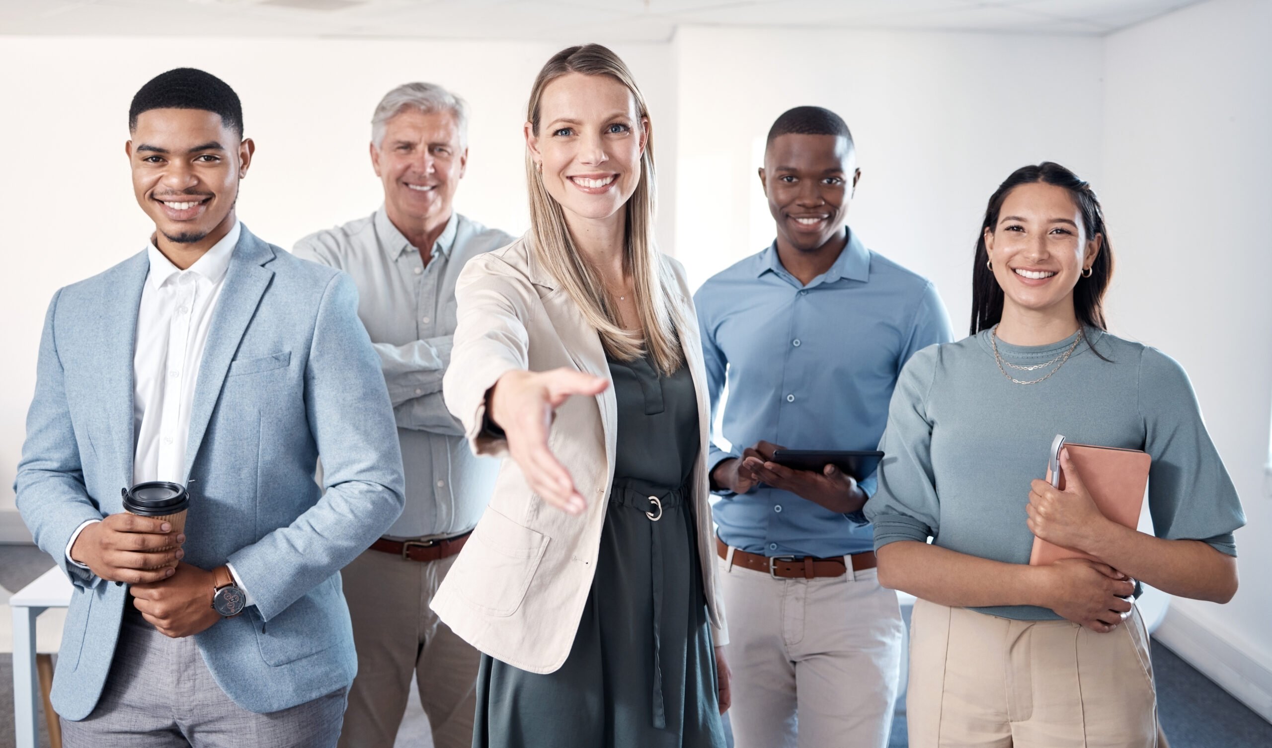 Une femme tend la main pour saluer, entourée d’une équipe souriante et professionnelle, symbolisant l’accueil et l’implication active des managers dans le recrutement.