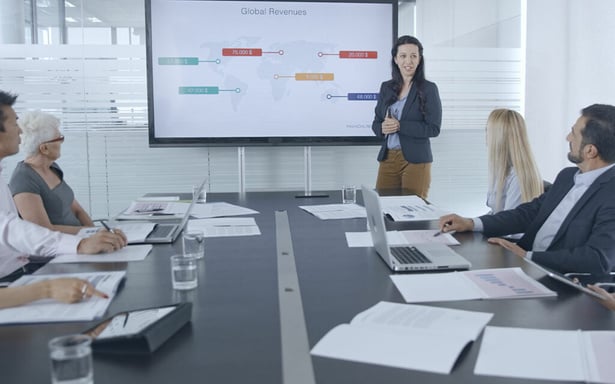 Une intervenante présente un tableau de bord à son équipe en réunion